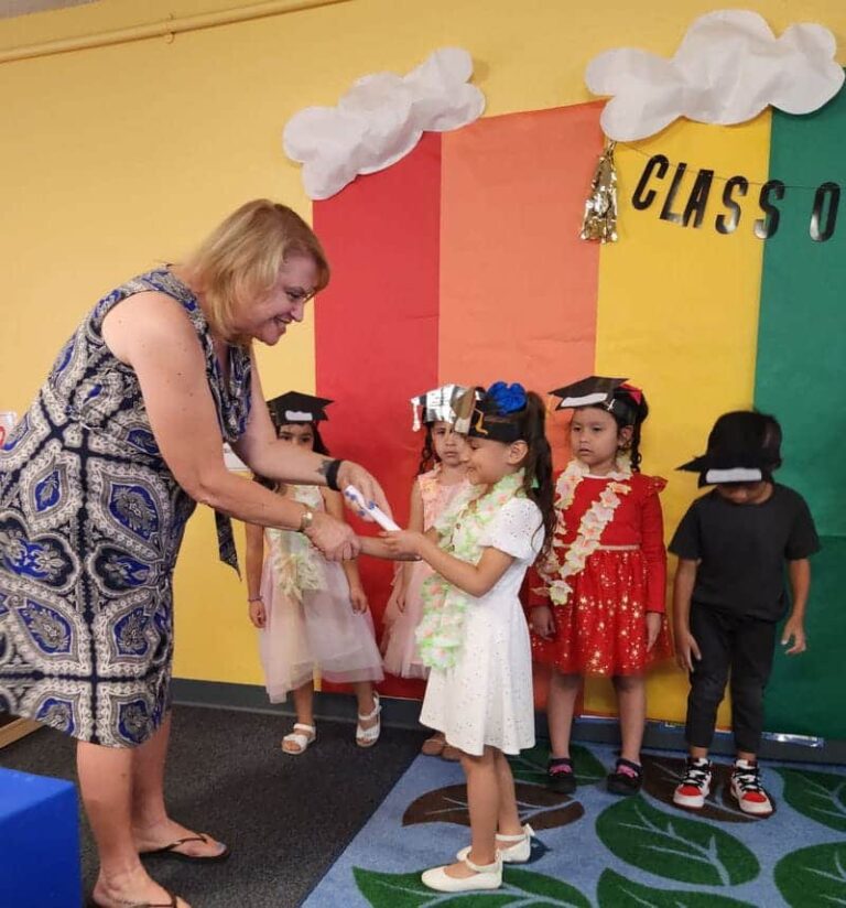 A teacher shaking hands with her students as they graduate from pre-K.