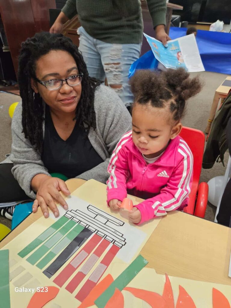 An Early Childhood educator assisting a young child with her crafts.