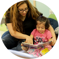 Mother reading a book with her young daughter, fostering learning and bonding as part of Sunrise Children's Foundation programs.