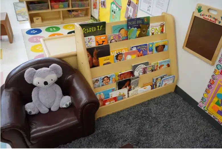 A reading section with a bookshelf and chair at Sunrise Children's Foundation.