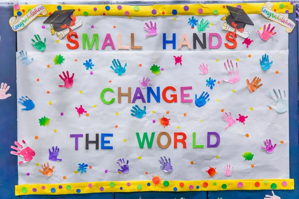 Bulletin board with 'Small Hands Change the World' for Head Start Awareness Month, vibrant handprints.