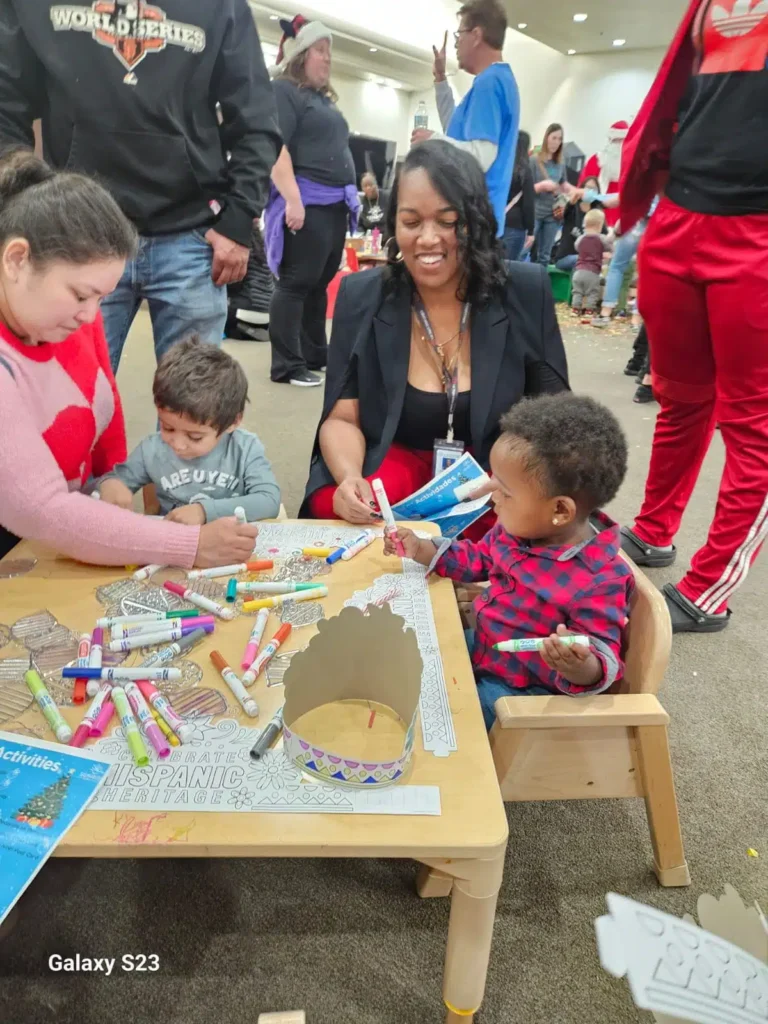Staff members from Sunrise Children’s Foundation are coloring with kids at a Christmas event.